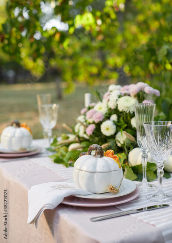 Table setting with beautiful autumn decorand with white mini pumpkins and crystal glasses for Thanksgiving Day or Halloween