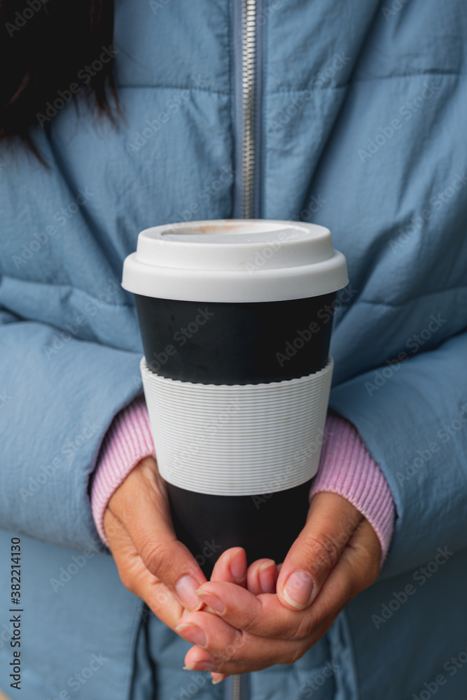 reusable Cup of coffee to take away in the hands of a girl. Keep your hands warm in the cold