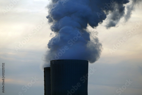 Smoke rising from a cooling tower of a power station, red-orange evening sky, concept of environmental protection, energy transition, electricity and climate change