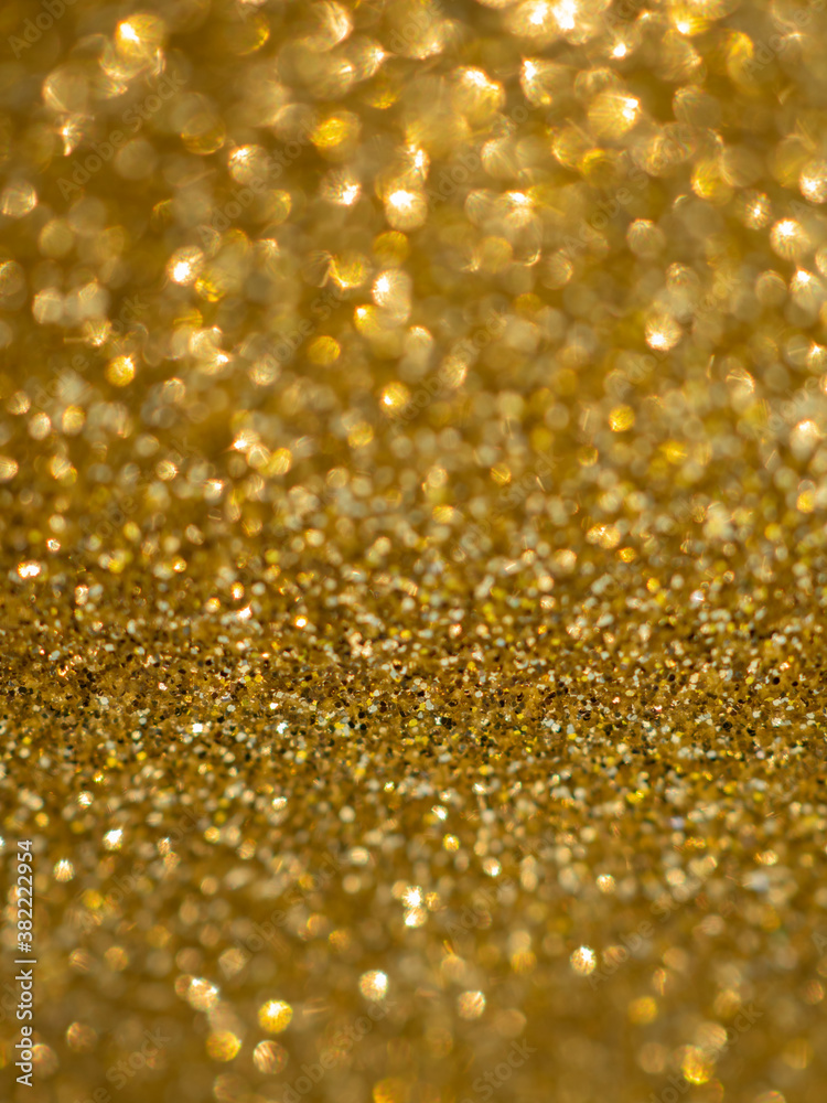 A glittery gold paper. Golden glitter light bokeh abstract texture. Pattern designs. Sparkle wallpaper for Christmas. Brilliance shimmering sequin background. Party time.