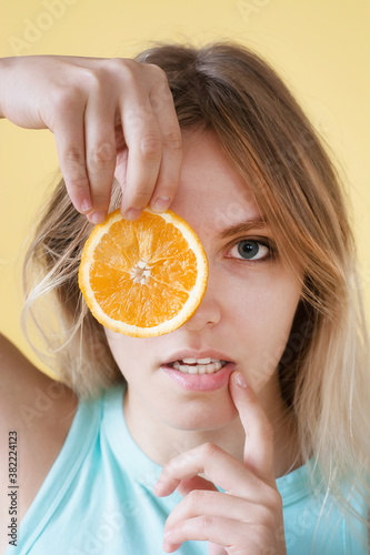 Portrait of a young woman getting funny with orange.