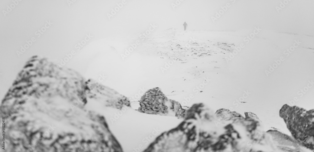 Man reaching summit of Y Garn in winter conditions with poor visibility in the mountains of Snowdonia National Park, Wales