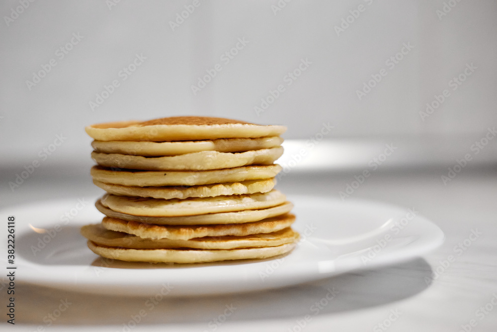 A stack of pancakes is on a white plate A stack of pancakes is on a white plate