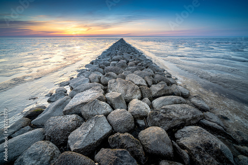 Fotobehang View of the stone embankment to prevent waves of the sea during sunset