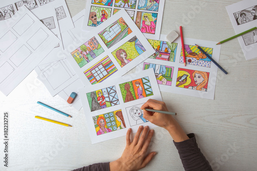 An animator painter draws a color storyboard for a comic book or movie. An illustrator seated at his desk creates a storyboard for a cartoon. photo