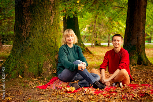 Beautiful woman,blonde,middle-aged,with a big son sitting under an autumn tree,in the Park,on a Sunny day © khanfus