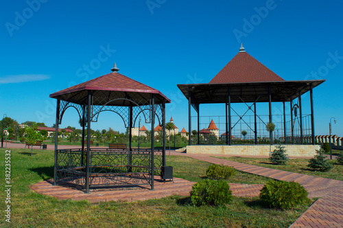 Two openwork gazebos for recreation of various forms in the park area. Making beautiful traditional wrought iron structures. Types of roofs and roof coverings, construction. © Viacheslav