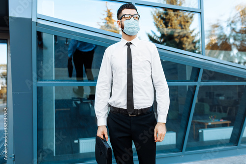 Man businessman in business clothes and a medical protective mask on his face, against the background of a glass office building, Quarantine, coronavirus, business, success © Shopping King Louie