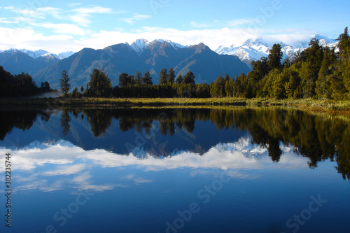 Mirrored lake with snow capped mountains in New Zealand, luxury travel, adventure, wild travel, great outdoors, grasslands, wetlands © Warped Out