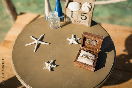 Fotografie Close up view of wedding rings inside wooden box on the table with decor of star