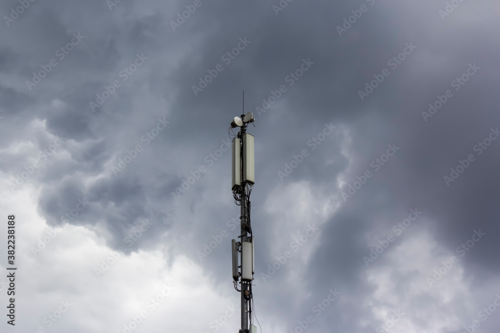 Telecommunications tower with 5G transmitters. A cellular base station with transmitting antennas on a telecommunications tower against a dark blue tinted sky. 3G, 4G and 5G cellular.