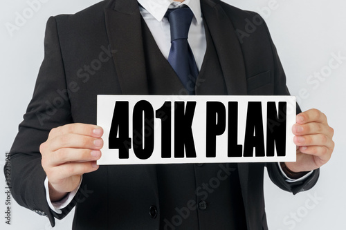 A businessman holds a sign in his hands which says 401K PLAN