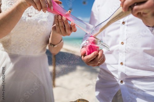 Slika na platnu Close up view of bride and groom filling color sand into the jar at the wedding