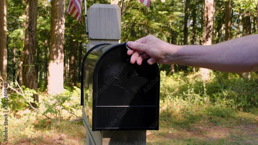 Absentee voter mailing vote by mail ballot in residential mailbox.