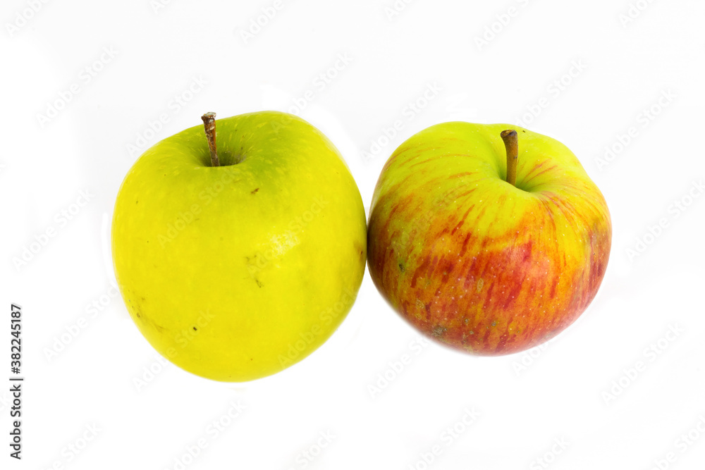 pair of ripe yellow apples and a red pair of fruit stand on an isolated white background