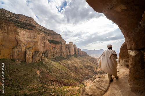 Rear view of priest walking on access trail to the rock-hewn Abuna Yemata Guh church, Gheralta Mountains, Tigray region, Ethiopia