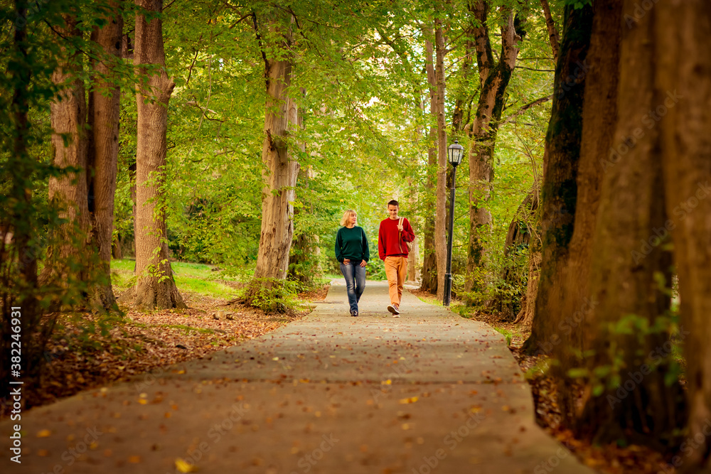 Obraz premium Beautiful woman,blonde,middle-aged,with a big son walking in the Park,a beautiful autumn day