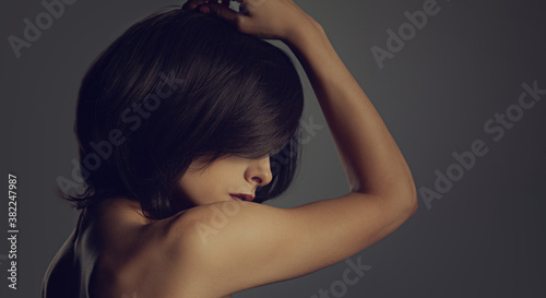 Foto Portrait of short hair black color woman looking down on black background