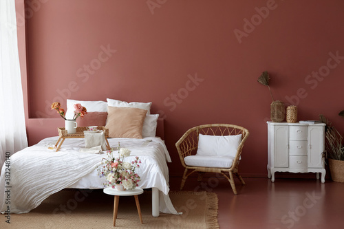 Cozy bedroom interior of retro armchair, vintage chest dwarf and bed on the background of the pink wall and painted wooden floor photo