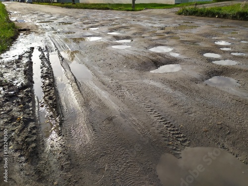 Old broken dirt road with holes and puddles
