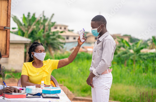 Canvastavla image of African health worker in face mask checking temperature during covid-19