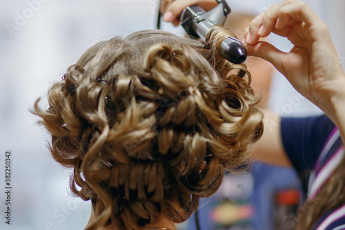 Hair curlers make curls on women's hair. Services of a hairdresser for evening and festive hairstyles concept