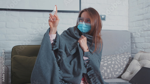 Paranoid young woman at home in face protection disinfecting air with sanitizer scared of germs contamination. Coronavirus anxiety. Mysophobia. Fear of infection. Lockdown isolation.