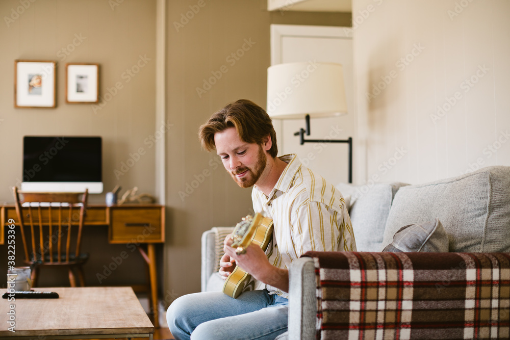 Man playing guitar on couch Man playing guitar on couch