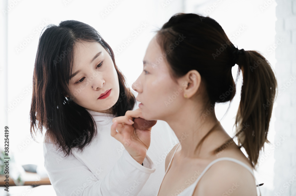 Female makeup artist applying makeup to model, preparing for photo shoot in studio Female makeup artist applying makeup to model, preparing for photo shoot in studio