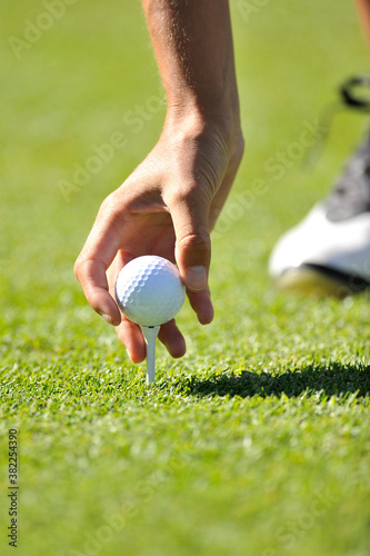 Golfer setting a ball on a tee