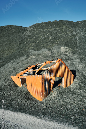 Old corrugated metal hut swalled by slate heap. Honister, Cumbria, UK. photo