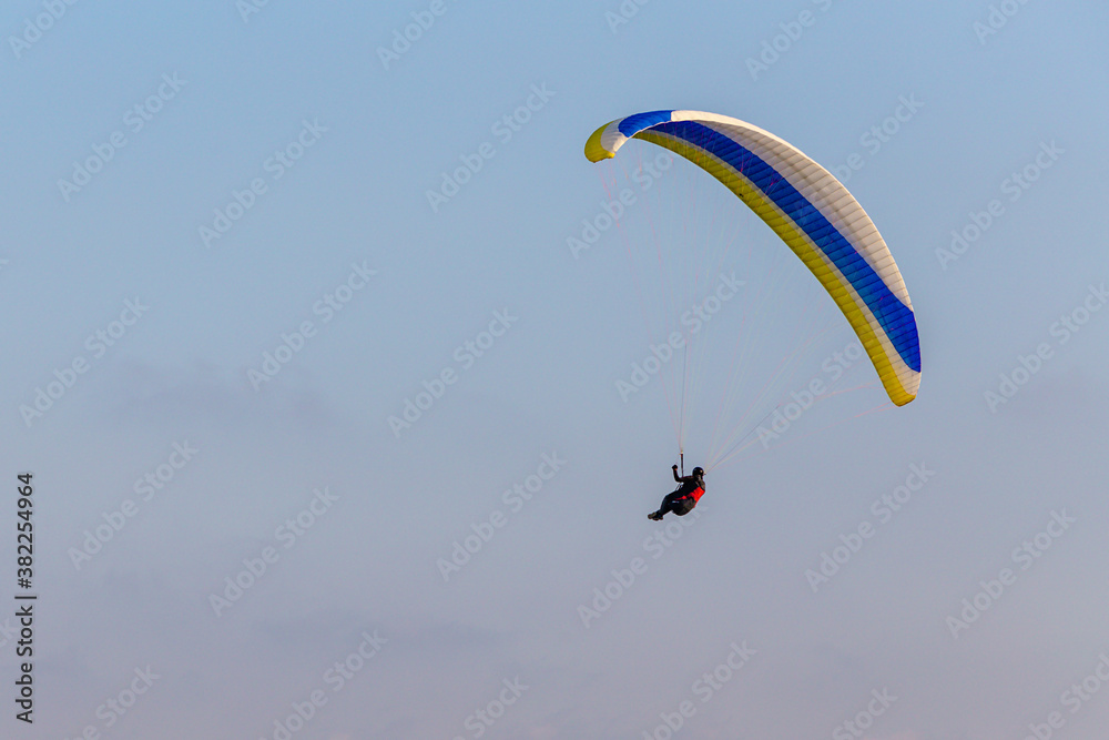 Paraglider flying over the sea coast in blue sky background Paraglider flying over the sea coast in blue sky background