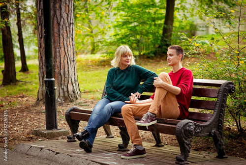Beautiful woman,blonde,middle-aged,with her son,sitting on a bench and talking