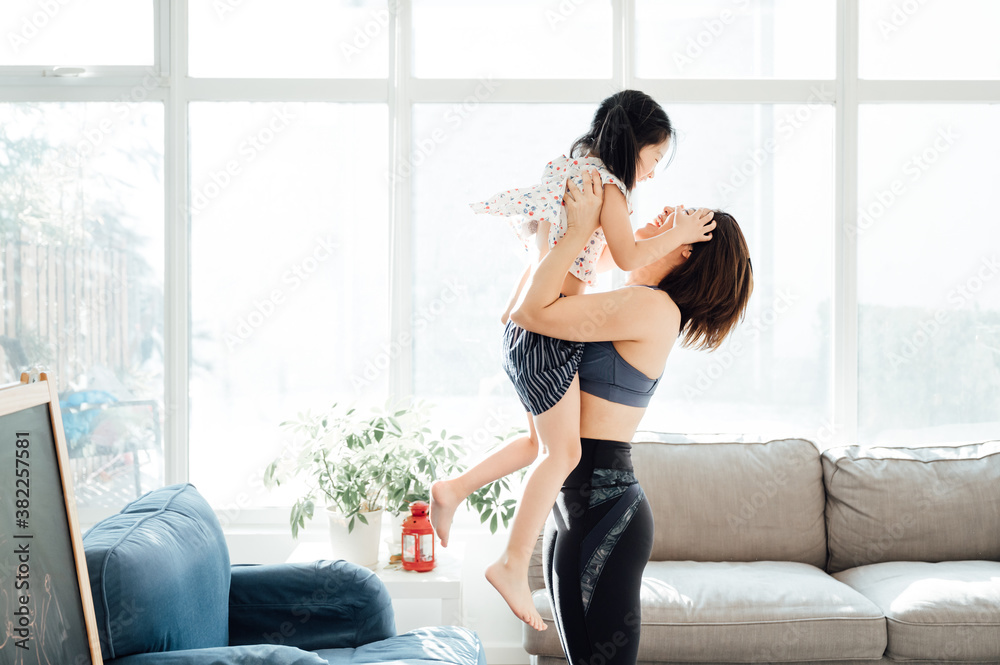 Asian young mom and daughter practicing yoga at home Asian young mom and daughter practicing yoga at home