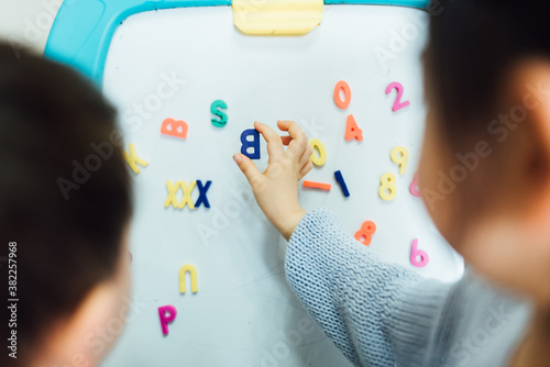 Cute toddler girl and boy learning before white board at home photo