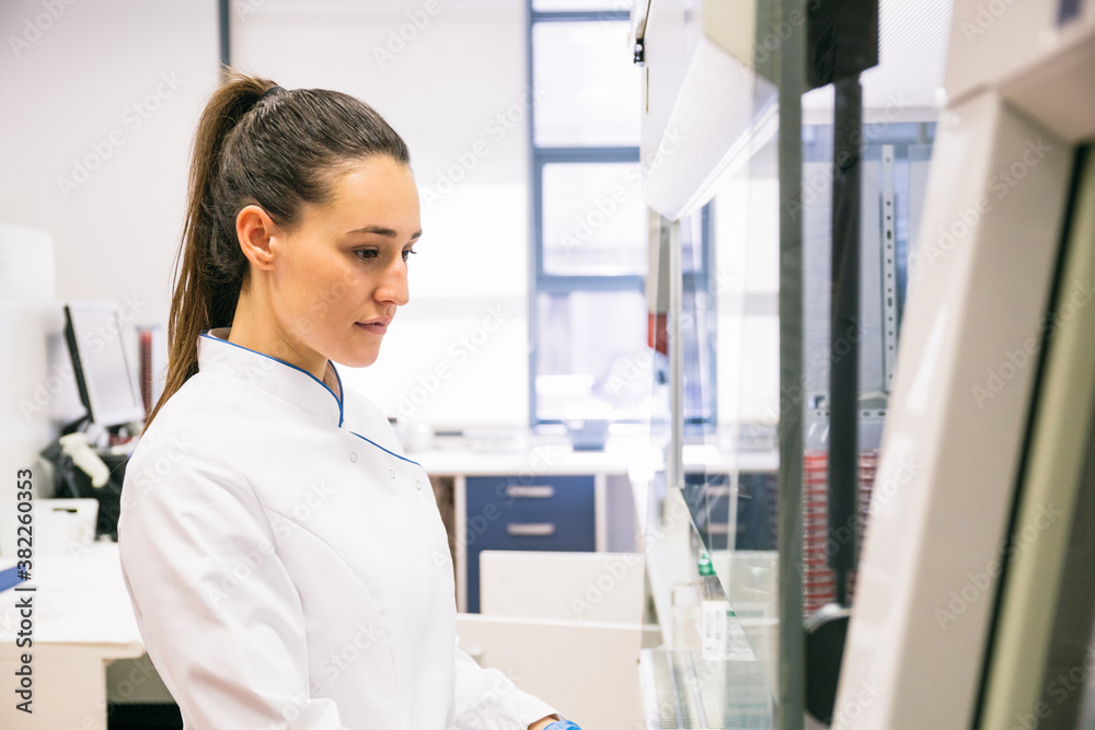 Side view of attractive female scientist in white apparel working in modern laboratory. Side view of attractive female scientist in white apparel working in modern laboratory.