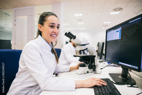 Lovely young woman in lb apparel smiling and using computer while working in innovative laboratory.