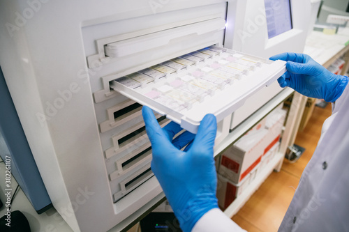 Wallpaper Mural Crop hands of scientist putting tray with samples into analyzer while working in modern lab Torontodigital.ca