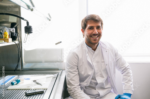 Man lab sitting looking at camera while working in microbiology laboratory photo