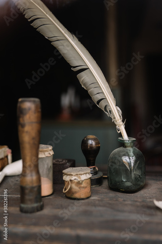 Feather pen with inkwell against dark background