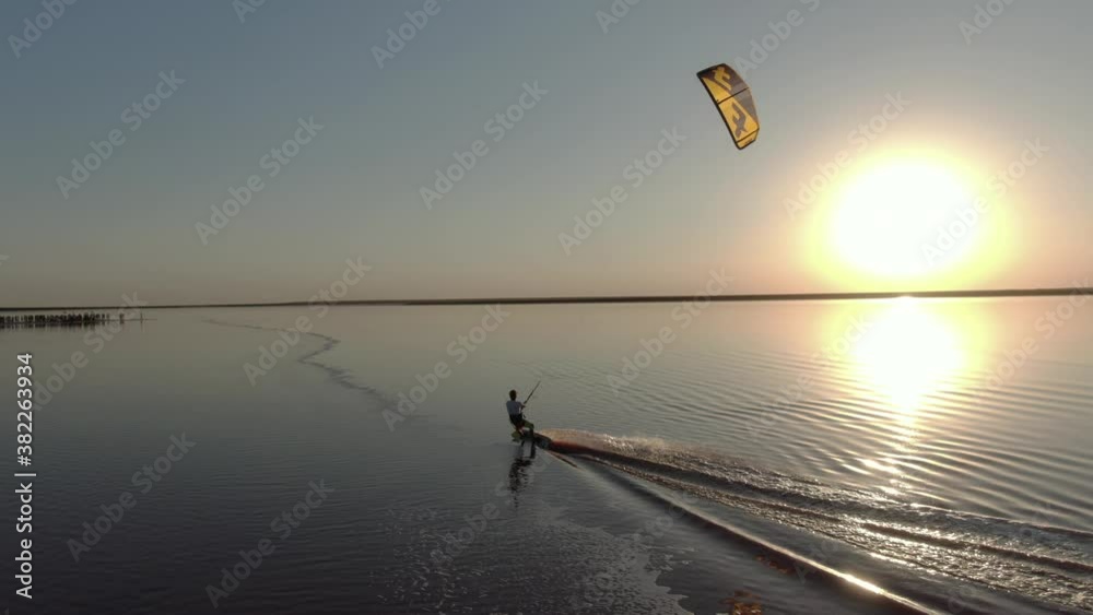 Aerial footage of a man kitesurfing on pink water of the lake, nature and sports