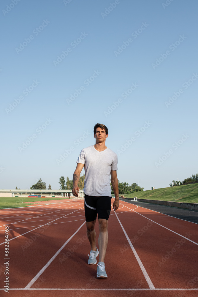 Serious athlete walking on track recovering breath