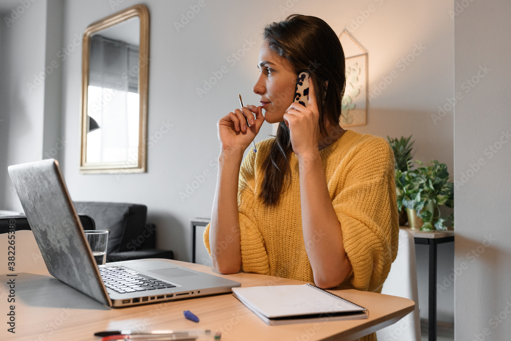 © Milles Studio/Stocksy - Thoughtful freelancer speaking on smartphone at home
