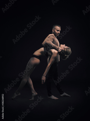girl with boyfriend perform beautiful gymnastic elements. beautiful acrobatic couple. black background