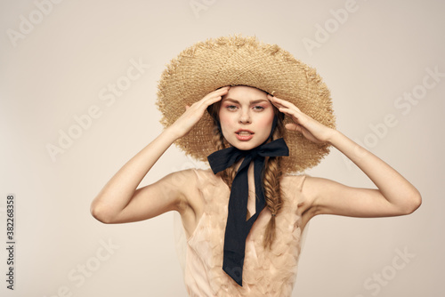 Romantic woman in a hat and dress on a light background gestures with her hands portrait fun emotions cropped view