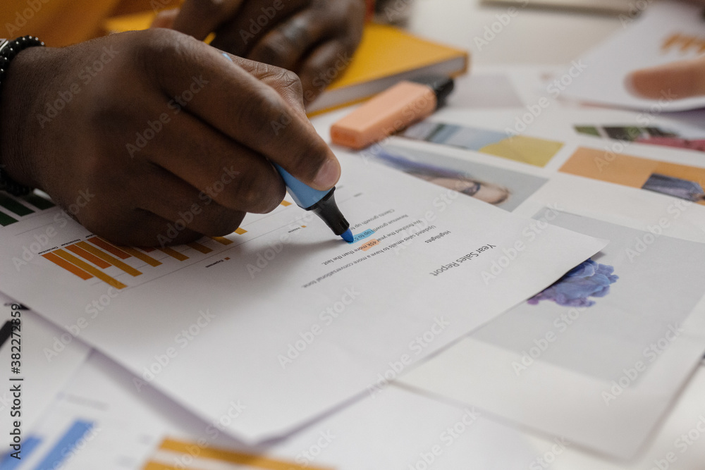 Crop black man highlighting data on paper Crop black man highlighting data on paper
