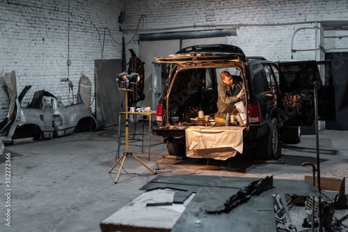Mechanic repairing car in dark garage photo