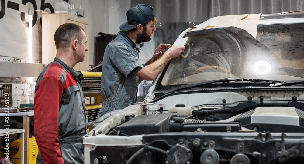 Male technicians comparing sample with car paint Male technicians comparing sample with car paint