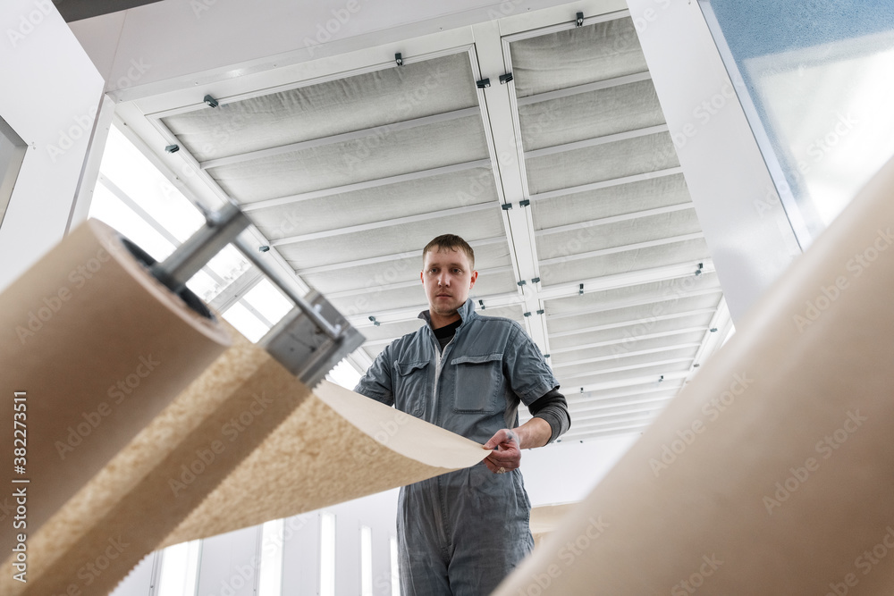 Male technician unrolling paper in garage Male technician unrolling paper in garage