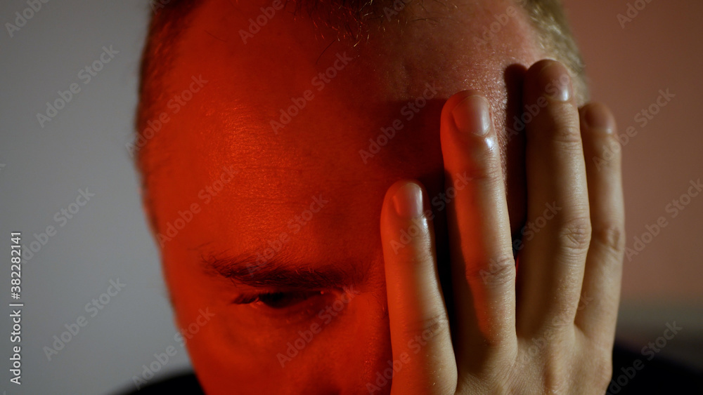 A young man with a serious look. Frowning man in red tones evil smile A young man with a serious look. Frowning man in red tones evil smile